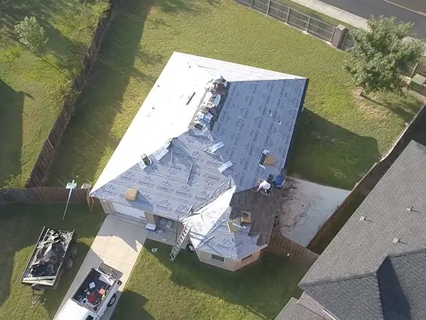 Crew installing new roof shingles on a home
